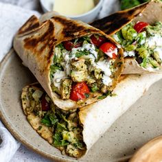 two burritos on a plate next to a bowl of ranch dressing