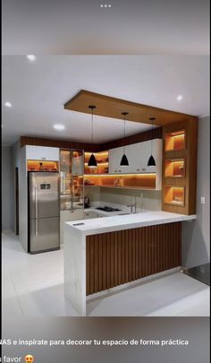 a modern kitchen with an island counter and stainless steel refrigerator freezer in the center