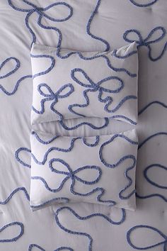 two pillows on a bed with blue and white lines all over them in the shape of hearts