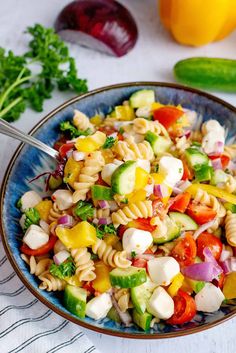 a bowl filled with pasta salad next to vegetables