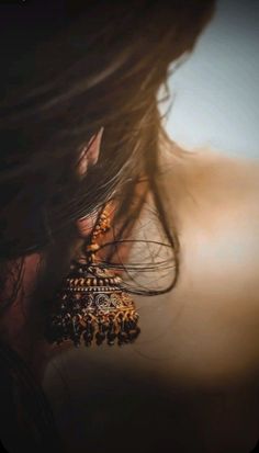 the back of a woman's head with earrings on it