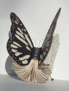 a black and white butterfly sitting on top of an open book with pages in it's wings