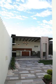 a modern house with an outdoor patio and covered in white tile, surrounded by greenery