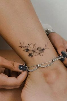 a woman with a tattoo on her arm holding onto a bracelet that has flowers on it