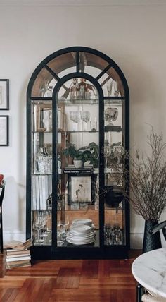 a black china cabinet with glass doors in a dining room next to a table and chairs