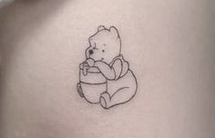 a small tattoo of a teddy bear holding a potted plant on the back of a woman's stomach