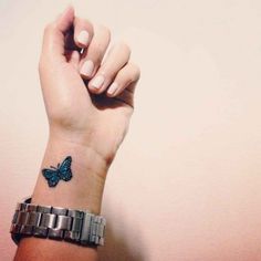 a woman's wrist with a small blue butterfly on the left side of her arm