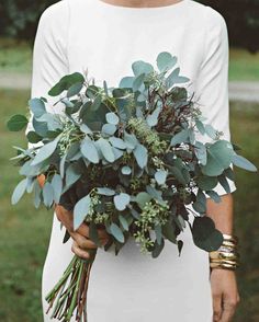 a woman holding a bouquet of greenery in her hands