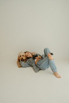 a woman laying on the ground with her dog next to her and holding a teddy bear