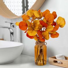 a vase filled with orange flowers sitting on top of a white counter next to a sink