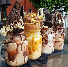 four jars filled with different types of ice cream and desserts on top of a table