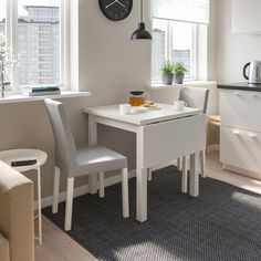 a white table with two chairs and a clock on the wall in a kitchen area