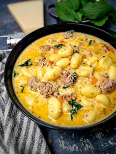 a black bowl filled with pasta and meat on top of a table next to cheese