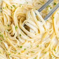 a fork in a pasta dish with white sauce and parsley