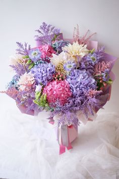 a bouquet of flowers sitting on top of a white table next to a pink ribbon