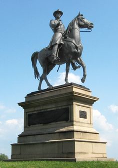 a statue of a man riding on the back of a horse in a grassy field