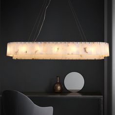 a modern chandelier hanging over a table with a chair and vase on it