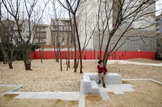 a young boy is running through the park in front of some trees and buildings with no leaves on them