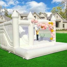 an inflatable bouncer with balloons and a man standing on the front lawn