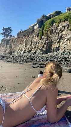 a woman laying on top of a beach next to the ocean