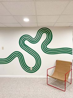 a chair sitting in front of a wall with a green and white design on it