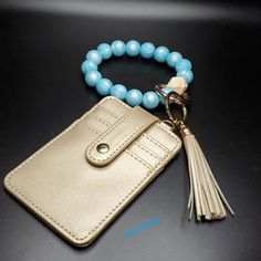 a gold wallet with a blue beaded bracelet and a tasseled keychain