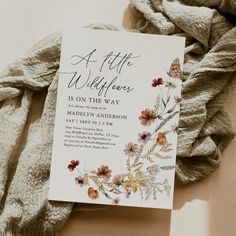 a white card with flowers on it sitting next to a pile of blankets and scarves