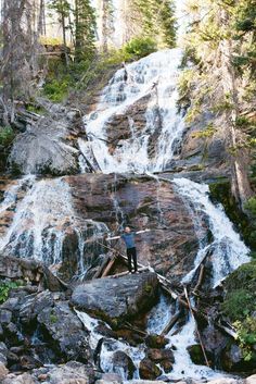 a man standing at the base of a waterfall