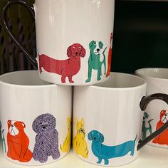 four coffee mugs with dogs painted on them are stacked up in front of each other