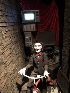 a creepy doll sitting in front of a tv and some wires on the ground next to it