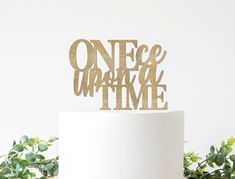 a white cake topped with a gold one piece cake topper