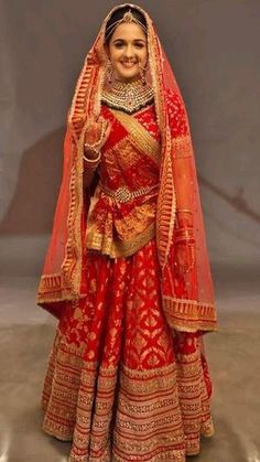 a woman in a red and gold bridal gown posing for the camera with her hand on her hip