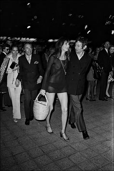 black and white photograph of two people walking in front of a group of other people