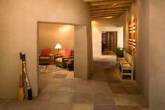 an empty hallway leading to a living room and dining area with chairs, couches and lamps on either side