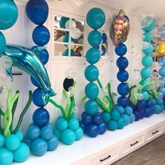 a room filled with blue balloons and sea animals on the wall next to each other