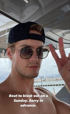 a shirtless man wearing sunglasses and a bandana making the peace sign with his hand