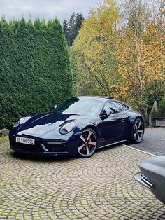 a blue sports car parked in front of a hedge