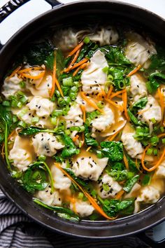 a pot filled with dumplings and vegetables on top of a stove burner next to a towel