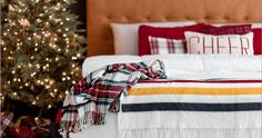 a christmas tree is in the background behind a bed with plaid blankets and throw pillows