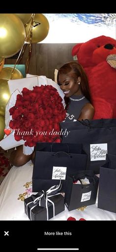 a woman holding a large bouquet of red roses in front of a giant teddy bear