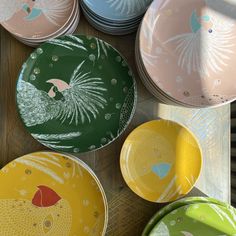 colorful plates with designs on them sitting on a wooden table next to other plates and bowls