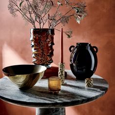 a table topped with vases filled with flowers on top of a wooden table next to a candle