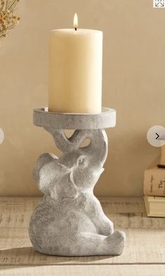 an elephant candle holder with a lit candle in it on a table next to some books