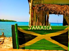 a green and yellow bench sitting on top of a beach next to the ocean in jamaica