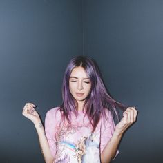 a woman with purple hair is holding something in her hands