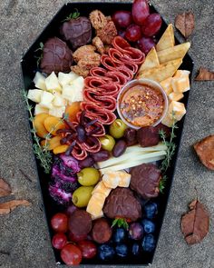 a tray filled with different types of cheeses and fruit next to crackers on the ground