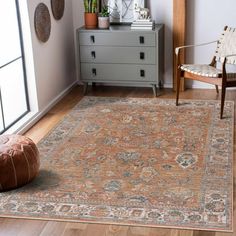 a living room area with a rug, chair and potted plant on the floor