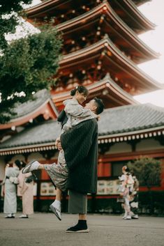 a woman holding a child in front of a pagoda