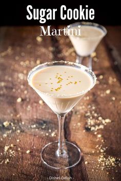 two martinis sitting on top of a wooden table next to each other, one filled with liquid and gold flakes