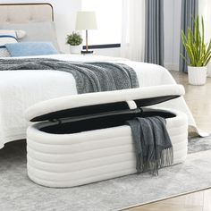 a bed with an open storage compartment on the side and a plant next to it